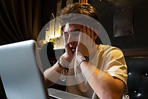 Young man sits at a table in front of a laptop.