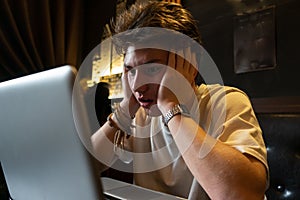 Young man sits at a table in front of a laptop.