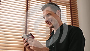 Young man sitting at table using online payment app. Adit