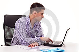 Young man sitting at the table and working on laptop