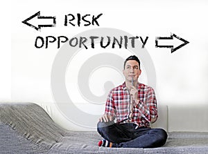 Young man sitting and thinking about choosing between taking risks and opportunities photo