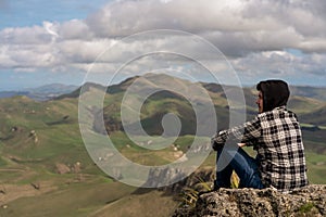 Young man sitting at the top of the mountain in Te Mata Park, Hawke`s Bay, New Zealand