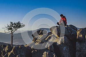Young man sitting on the top of the rock in sunrise