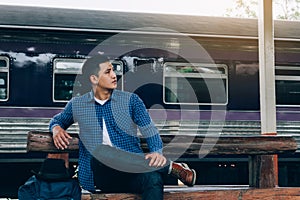 Young man sitting at train station with awaiting the train`s arrival