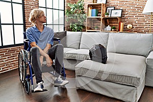 Young man sitting on wheelchair at for motorcycle accident looking to side, relax profile pose with natural face with confident