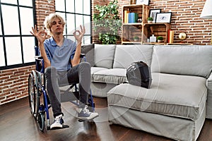 Young man sitting on wheelchair at for motorcycle accident relax and smiling with eyes closed doing meditation gesture with