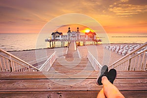 Young man sitting on wooden pier enjoying sunrise at Seebrucke Sellin, Baltic Sea, Germany