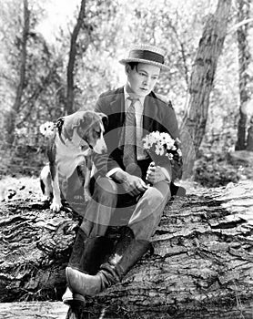 Young man sitting in the woods with his dog looking forlorn photo