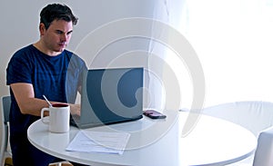 Young man sitting and working on laptop at home. Working father concept. Teleworking concept photo