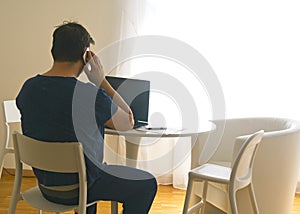 Young man sitting and working on laptop at home speaking to the mobile. Working father concept. teleworking concept