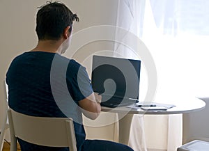 Young man sitting and working on laptop at home. Working father concept. teleworking concept