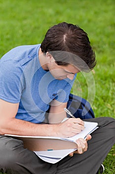 Young man sitting while writing on his notebook