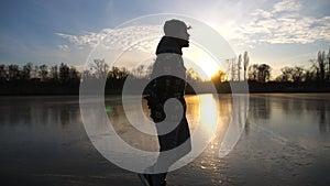 Young man skating on frozen river during sunset time. Guy shod in figure skates sliding on icy lake during training