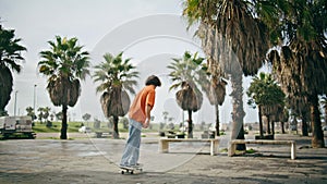 Young man skating longboard at park pavement. Hipster balancing on skateboard.