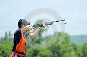 Young man skeet shooting with airborne shell