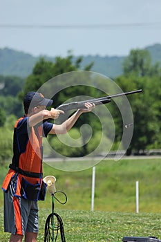 Young man skeet shooting with airborne shell photo