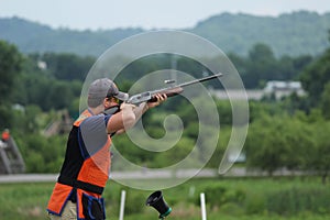 Young man skeet shooting with airborne shell photo