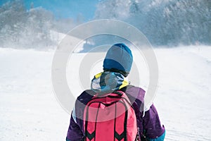 Young man in ski clothes looking at the top of the mountain. Skier skiing in the snow storm. Adventurer person hiking the peak of