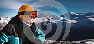 young man in ski goggles on a snowy mountain on a sunny day. close-up of a man looking to the side, enjoying the