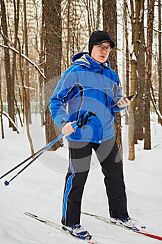 Young man on ski with ski-poles in one hand and