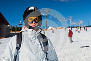A young man in ski suit, with helmet and ski goggles standing in