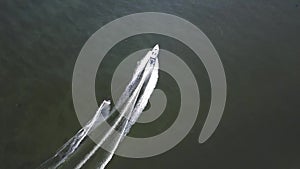 A young man is skiing. A sports guy is skiing on the water behind a boat. Top view from a drone.