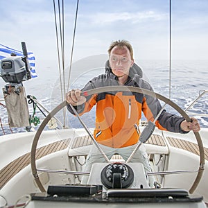 Young man Skipper early in the morning at the helm of a yacht in the open sea. Sport.