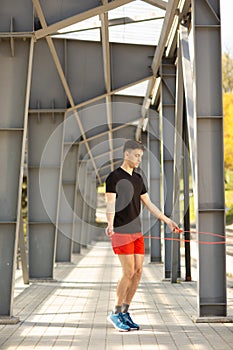 Young man skipping with jump rope outdoors. Exercising and lifestyle concept