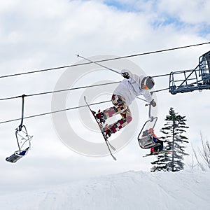 Young man on skis jumping in the air at ski resort.