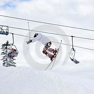 Young man on skis jumping in the air at ski resort.