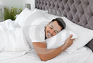 Young man sleeping in bed with soft pillows