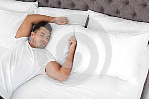 Young man sleeping on bed with soft pillows