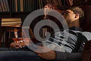 Young Man Sleeping on the Chair Holding a Book