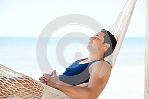 Young man sleeping in a hammock at the beach