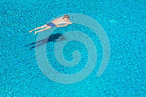 Young man sleeping peacefully on lifebuoy in swimming pool