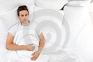 Young man sleeping on soft pillows in bed