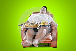 Young man sleeps with junk foods on the armchair