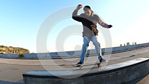 Young man slides on a skateboard along the ledge