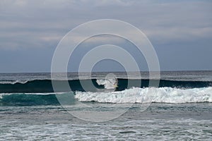 Young man sliding down a wave on a yellow surfboard. Surfer on a yellow surfboard on the crest of the wave. Young surfer learns to