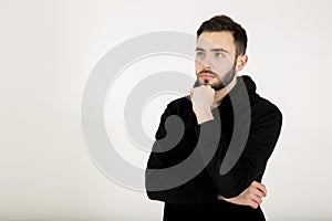 Young man with a small beard in black clothes is standing with