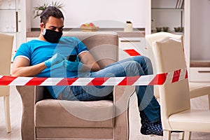 Young man with smartphone at home during pandemic