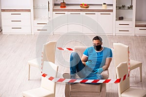 Young man with smartphone at home during pandemic