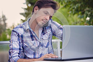 Young man with smartphone and laptop working outdoor