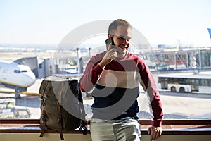 Young man smiles confident while talking on his phone from the airport