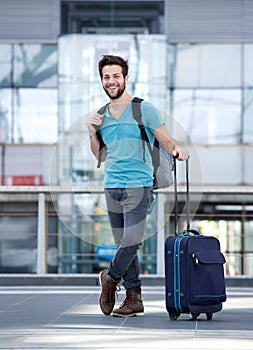 Young man smiling with bags at airport