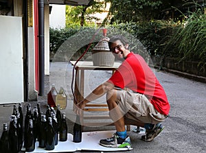 Young man smiling while bottling the wine at home