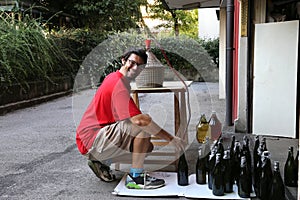 Young man smiling while bottling the wine at home