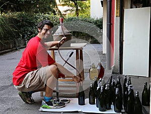 Young man smiling while bottling the wine at home