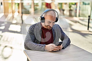 Young man smiling confident listening to music at coffee shop terrace