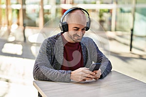 Young man smiling confident listening to music at coffee shop terrace